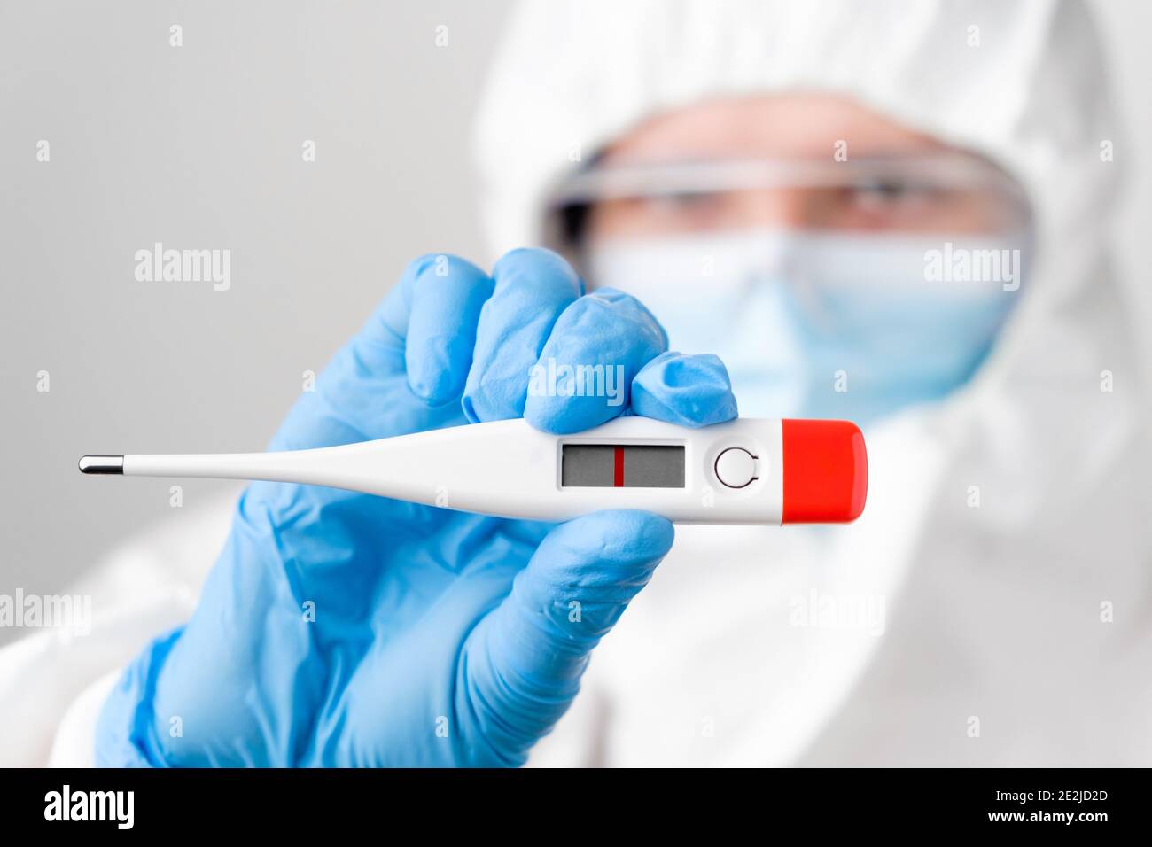 Negative pregnancy test in doctors hand in protective suit PPE, rubber gloves, face mask, safety glasses. Pregnancy during pandemic of coronavirus.  Stock Photo