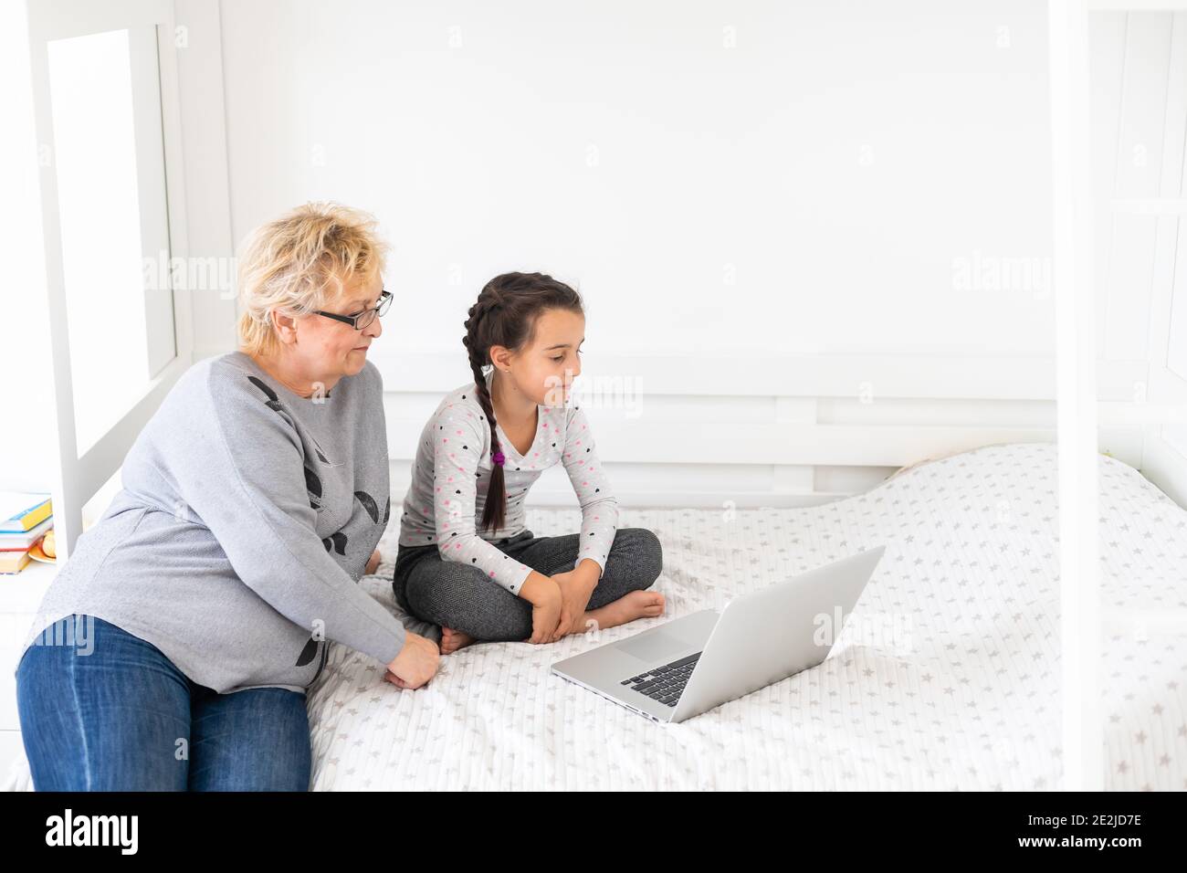 Cute and happy little girl child using laptop computer with her grandma ...