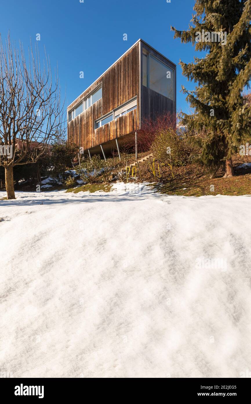 Modern minimal wooden house exterior. The season is winter and therefore you can see the snow in the garden Stock Photo