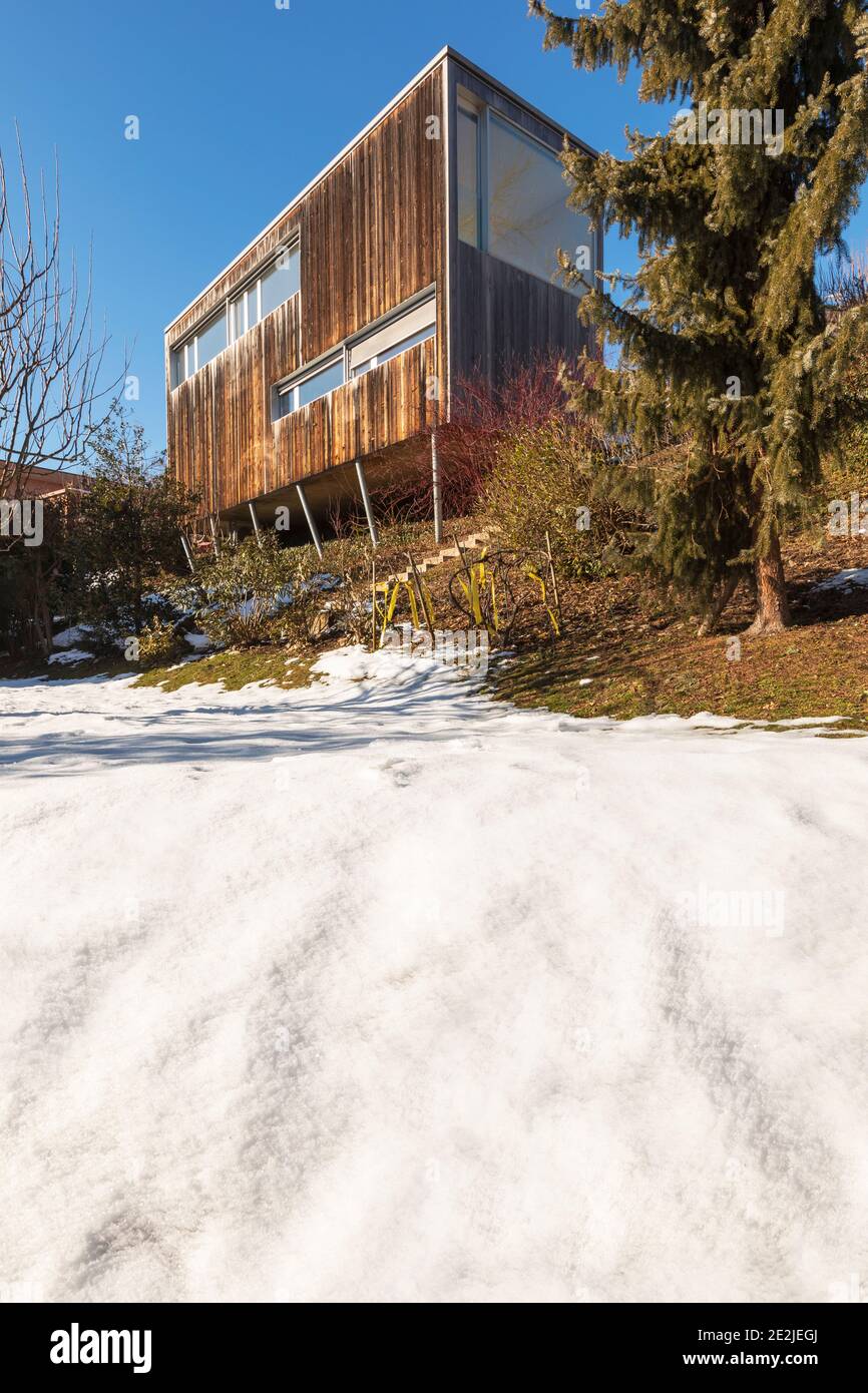 Modern minimal wooden house exterior. The season is winter and therefore you can see the snow in the garden Stock Photo