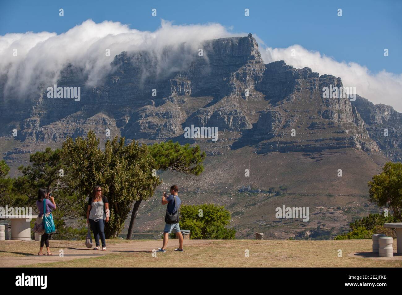 Tourists having their photograph taken with flat-topped Table Mountain tourist attraction in the distance, Cape Town, South Africa. Stock Photo