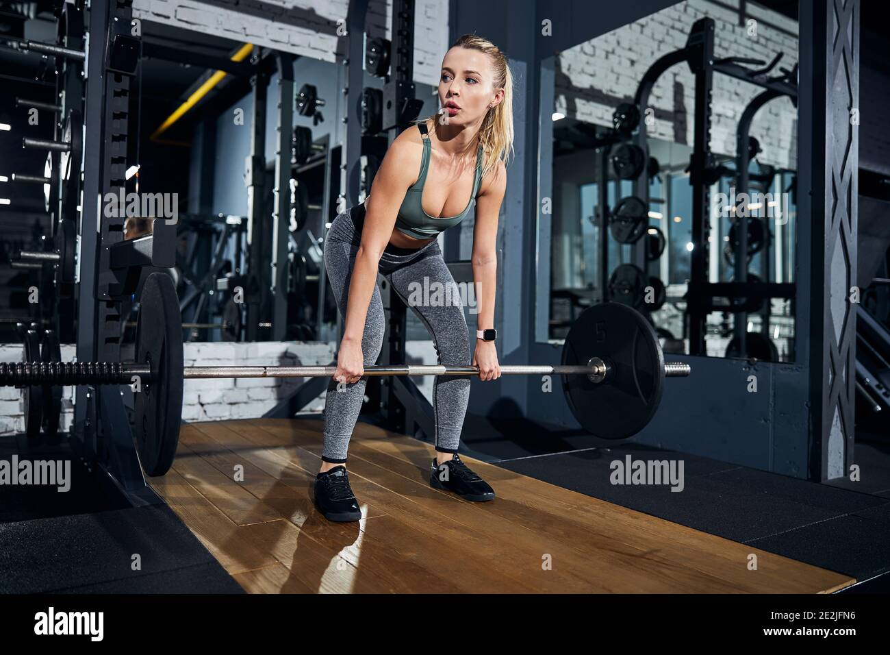 Careful weightlifter letting down a sizeable barbell Stock Photo