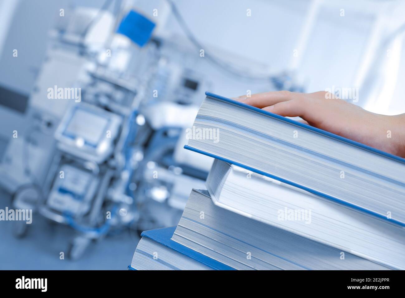 Medicine and studies. A stack of books at hand of Doctor or student are in a hospital ward Stock Photo