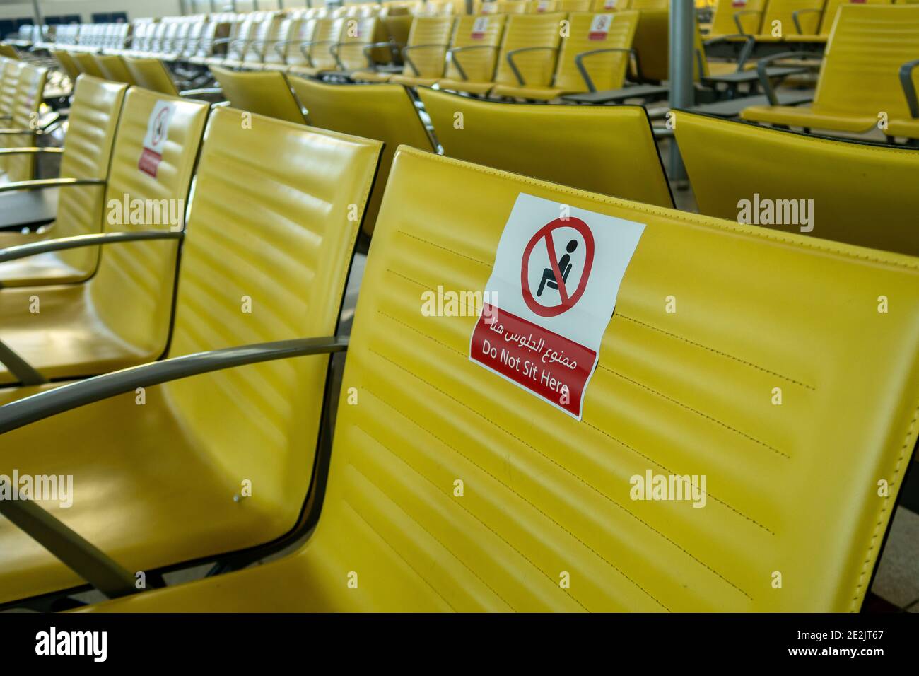 Rows of empty seats at Dubai International Airport DXB terminal with Do not seat signs due to coronavirus pandemic. Stock Photo