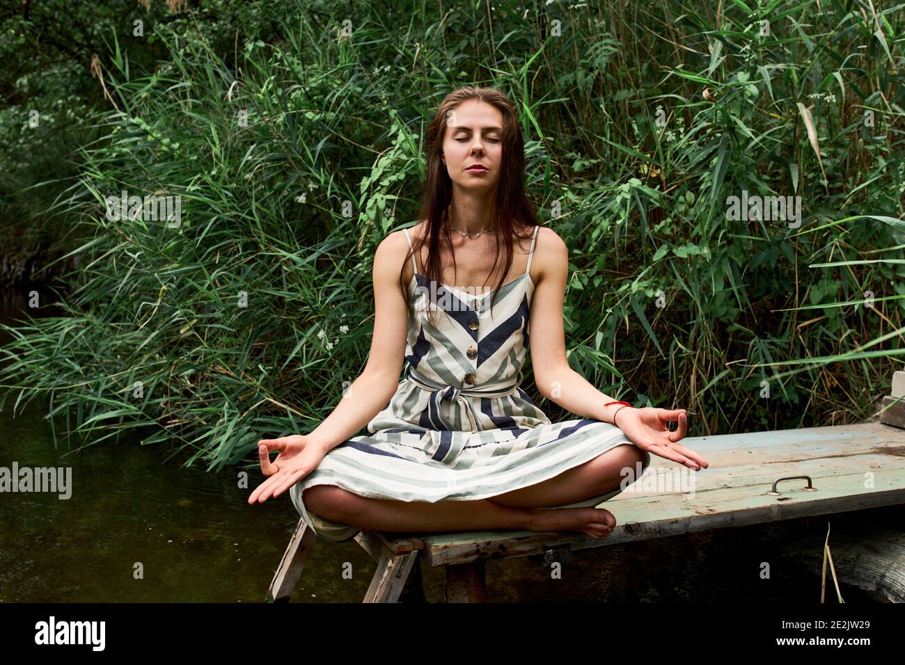 Beautiful young woman meditating and sitting on lotus pose in the ...