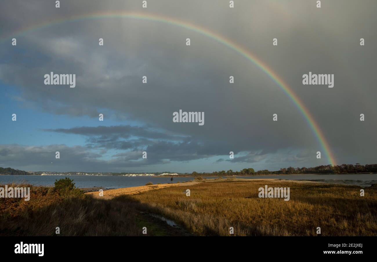 Rainbow over shingle headland in Poole Harbour in stormy weather in winter. Dorset. Stock Photo