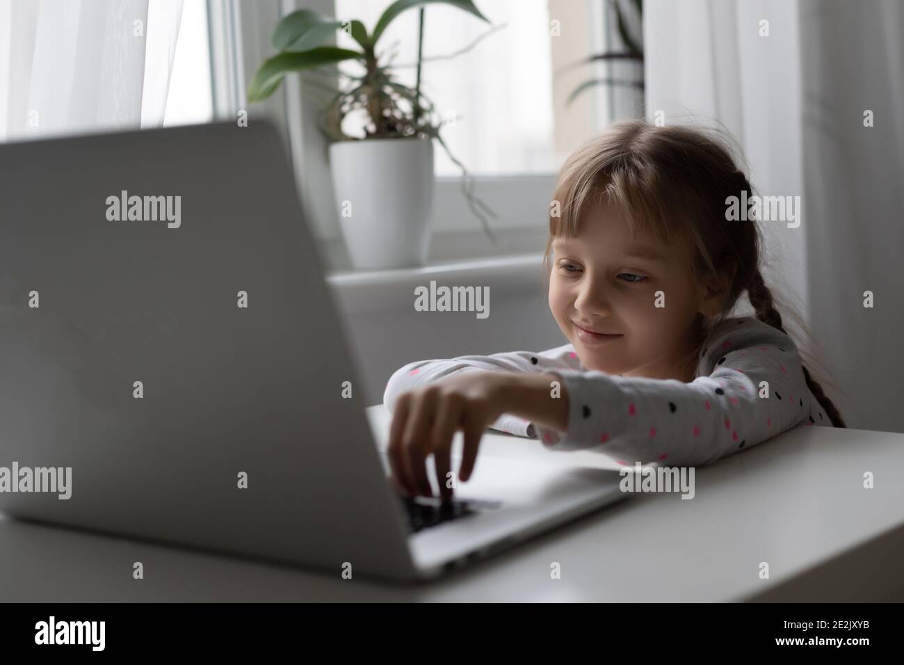 Little girl studying online using her laptop at home Stock Photo - Alamy