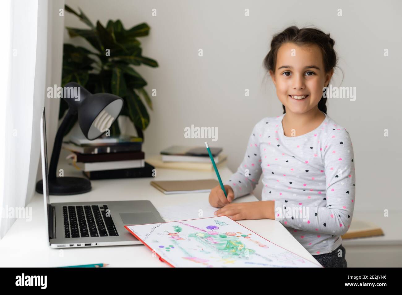 Little girl studying online using her laptop at home Stock Photo - Alamy