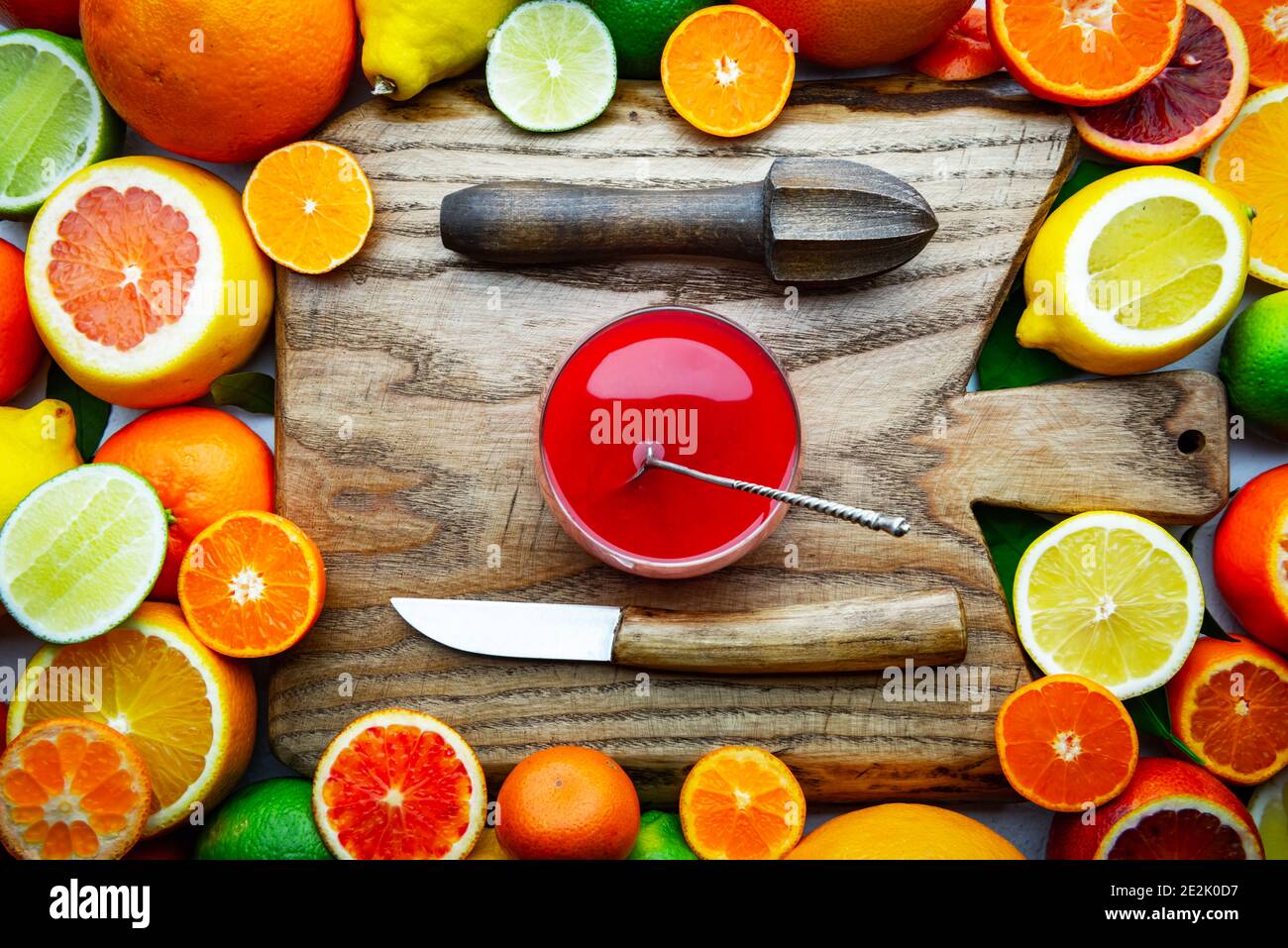 Mix of different citrus fruits and glass of juice with wooden board, squeezer and knife closeup. Healthy diet vitamin concept. Food photography Stock Photo