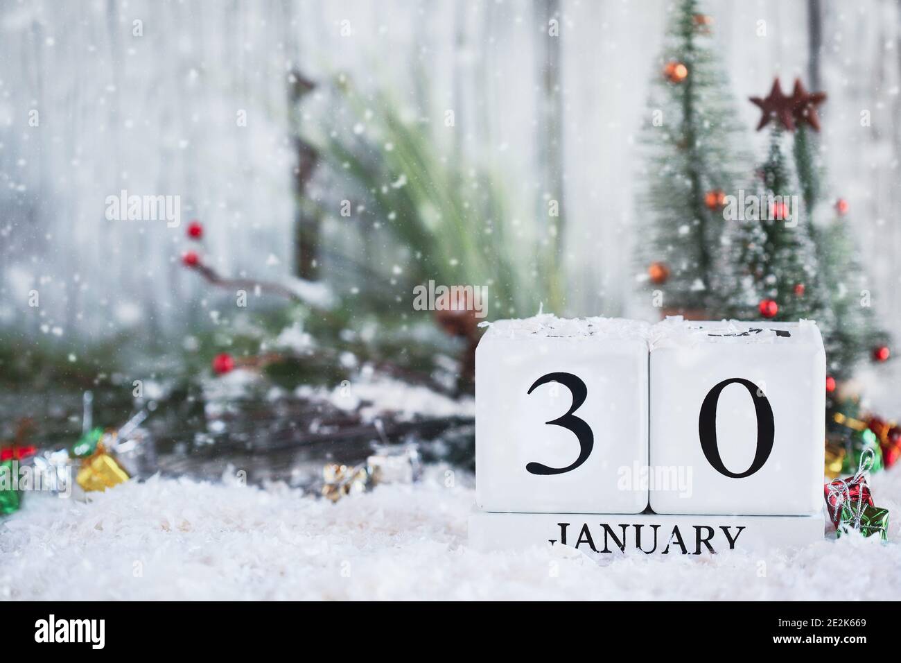 White wood calendar blocks with the date January 30th and Christmas decorations with snow. Selective focus with blurred background. Stock Photo