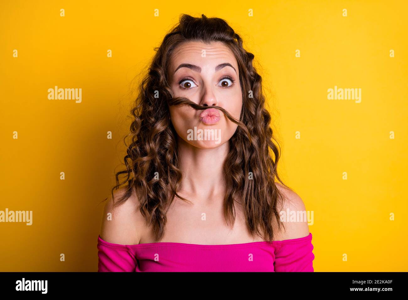 Photo portrait of girl making fake mustache pouting wearing pink crop-top isolated on vivid yellow colored background Stock Photo