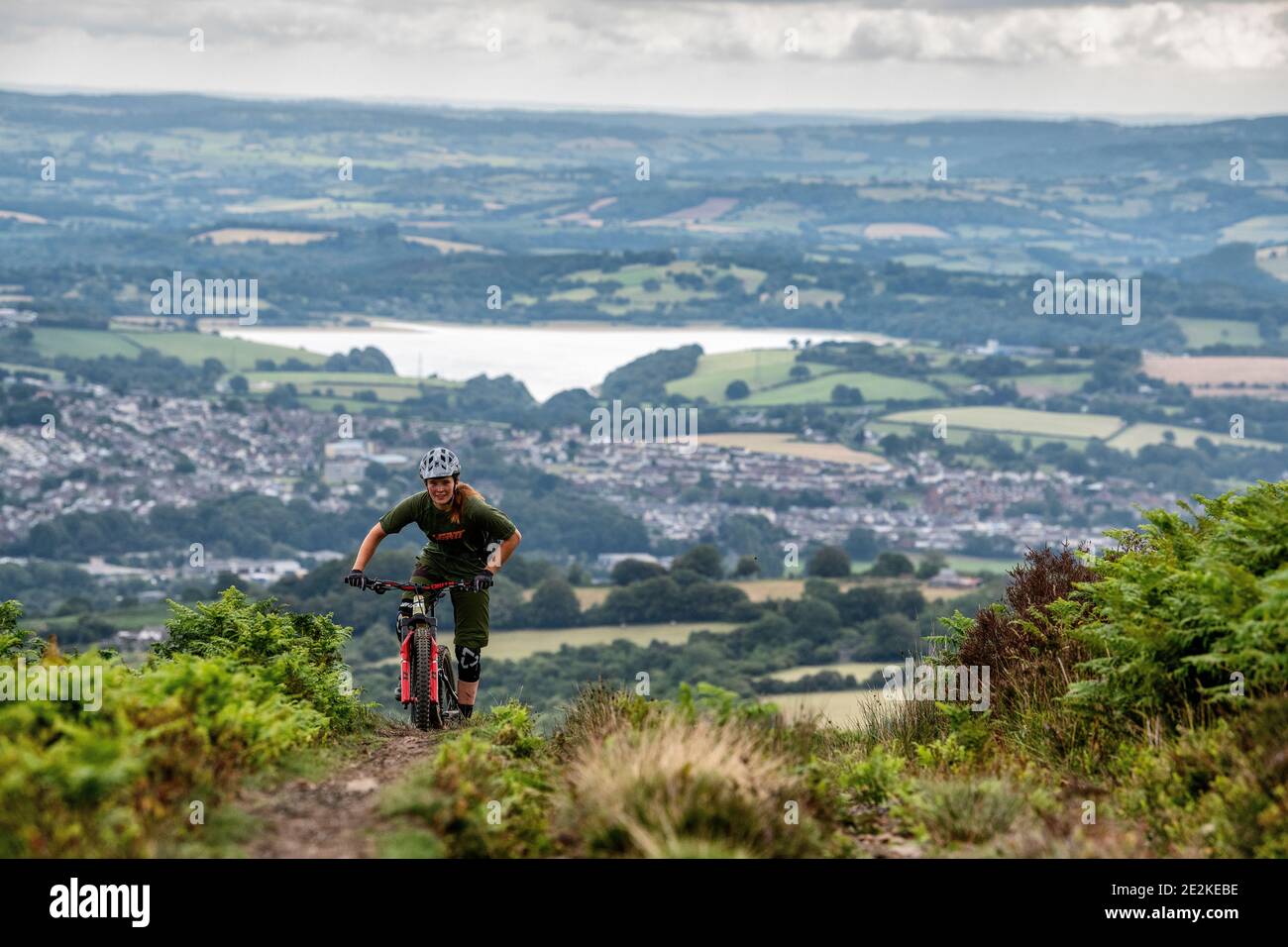 A woman rides a mountain bike uphill on a trail in the hills above pontypool and Cwmbran in Torfaen, Wales. Stock Photo