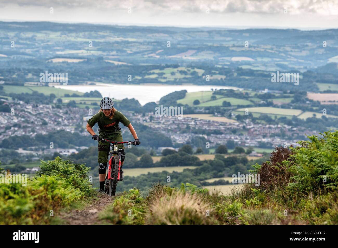 A woman rides a mountain bike uphill on a trail in the hills above pontypool and Cwmbran in Torfaen, Wales. Stock Photo
