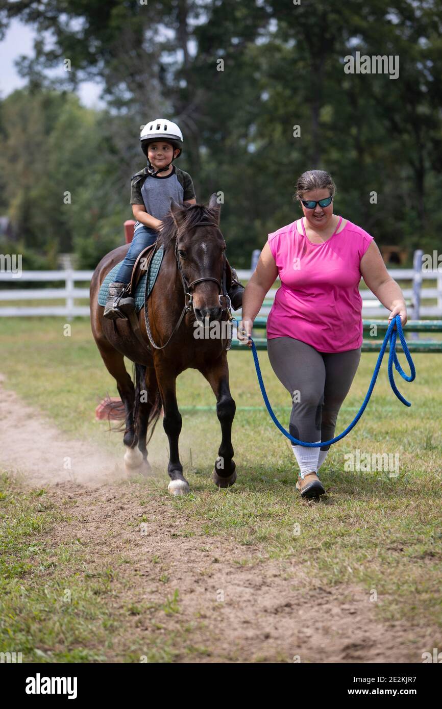 Woman leading a boy riding a pony. Stock Photo