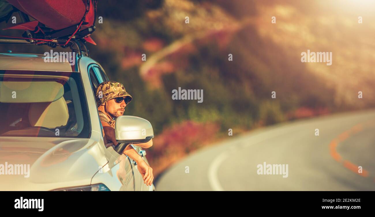 Traveler and Summer Grand Touring with Kayaks on the Vehicle Roof. Vacation Time Wilderness Exploring. Outdoor and Lifestyle Theme. Caucasian Driver i Stock Photo