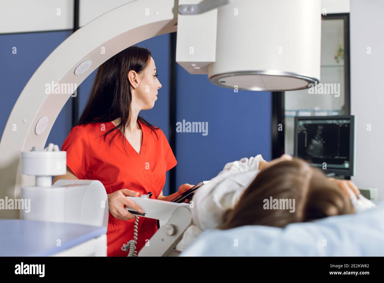 Extracorporeal Shock Wave Therapy. Kidney stone treatment. Side view of woman doctor looking at the digital screen of the lithotriptor to determine Stock Photo