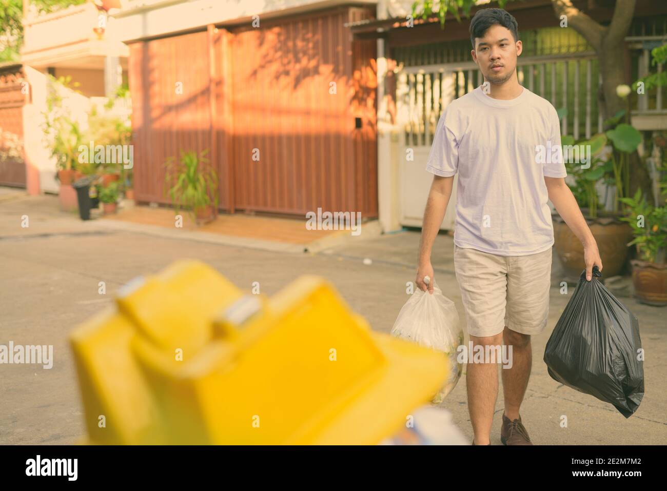 Young Asian man taking out the garbage at home Stock Photo