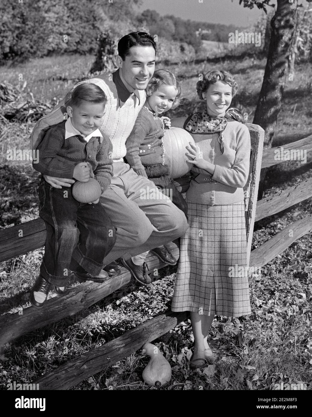 1950s SMILING FAMILY IN AUTUMN HOLDING PUMPKINS FATHER DAUGHTER AND SON SITTING ON WOODEN SPLIT RAIL FENCE MOTHER STANDING - c4912 HAR001 HARS FENCE FOUR AUTUMN MOM WOODEN CLOTHING NOSTALGIC FALL PAIR 4 LEAVES MOTHERS OLD TIME NOSTALGIA BROTHER OLD FASHION SISTER 1 JUVENILE STYLE SONS PLEASED FAMILIES JOY LIFESTYLE SATISFACTION FEMALES MARRIED BROTHERS RURAL SPOUSE HUSBANDS HOME LIFE NATURE COPY SPACE FRIENDSHIP FULL-LENGTH HALF-LENGTH LADIES DAUGHTERS PERSONS MALES SIBLINGS SISTERS FATHERS AGRICULTURE B&W PARTNER HAPPINESS CHEERFUL PUMPKINS STYLES AND DADS EXTERIOR FALL SEASON PRIDE SIBLING Stock Photo