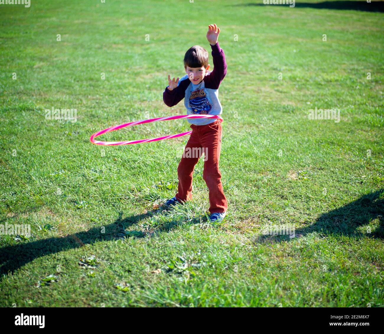 1980s BOY PLAYING WITH HULA HOOP - cj001197 CAM001 HARS SKILL ACTIVITY PHYSICAL HIGH ANGLE ADVENTURE STRENGTH RECREATION CAM001 PRIDE FAD FLEXIBILITY MUSCLES HULA HOOP JUVENILES TWIRL CAUCASIAN ETHNICITY OLD FASHIONED SPIN TWIRLING Stock Photo