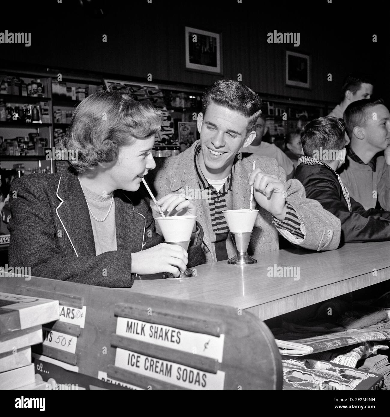 1950s TEENAGE COUPLE BOY AND GIRL SITTING TOGETHER DRINKING SOFT DRINKS AT SODA FOUNTAIN COUNTER LAUGHING SMILING FLIRTING - f8345 HAR001 HARS OLD FASHION 1 JUVENILE COMMUNICATION PLEASED JOY LIFESTYLE FEMALES HEALTHINESS COPY SPACE FRIENDSHIP HALF-LENGTH PERSONS CARING MALES TEENAGE GIRL TEENAGE BOY CUPS B&W DATING HAPPINESS CHEERFUL LOW ANGLE ATTRACTION SMILES COURTSHIP CONCEPTUAL JOYFUL MILKSHAKES TEENAGED POSSIBILITY GROWTH JUVENILES SOCIAL ACTIVITY TOGETHERNESS BLACK AND WHITE CAUCASIAN ETHNICITY COURTING HAR001 OLD FASHIONED Stock Photo