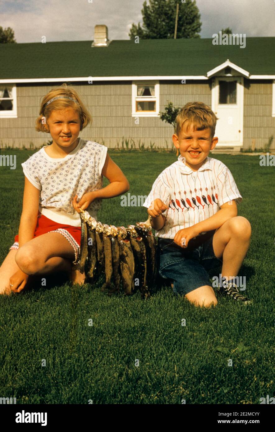 amateur boy girl cam 1950s BOY AND GIRL LOOKING AT CAMERA DISPLAYING FISH CATCH IN KNEELING  TOGETHER BACKYARD - ka7370 KNA001 HARS RELAXING PLEASED FAMILIES JOY  LIFESTYLE SATISFACTION FEMALES HOUSES BROTHERS HOME LIFE COPY SPACE CATCH