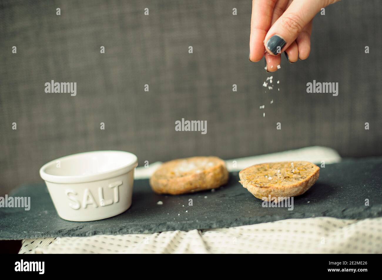 A pinch of salt. Close-up of fingers salting gluten-free homemade scones. Stock Photo