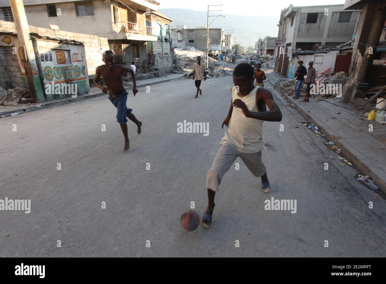 Young men play football barefoot on a street of Port-au-Prince, Haiti on Sunday February 7, 2010. Life gets almost to normal 3 weeks after January 12th devastating earthquake. A woman passing by said with dark humor taking pix of kids playing in the actual situation, makes no sense. Photo by Normand Blouin/ABACAPRESS.COM Stock Photo