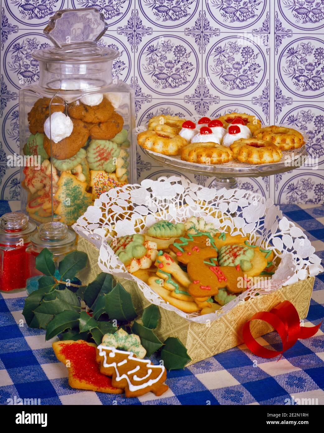 1970s ICED AND DECORATED HOME BAKED CHRISTMAS HOLIDAY COOKIES IN JAR ON A PLATE AND IN A BOX WITH PAPER LACE DOILY - kx9393 HAR001 HARS STILL LIFE SPRINKLES DOILY CHERRIES HOMEMADE JOYOUS HAR001 OLD FASHIONED Stock Photo