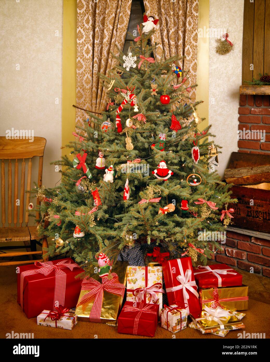 1980s SIMPLE EVERGREEN CHRISTMAS TREE DECORATED WITH HOMEMADE AND HANDMADE ORNAMENTS WRAPPED GIFTS AND PRESENTS AROUND THE BASE - kx9752 TEU001 HARS JOYOUS RELAXATION TOGETHERNESS HANDMADE OLD FASHIONED Stock Photo