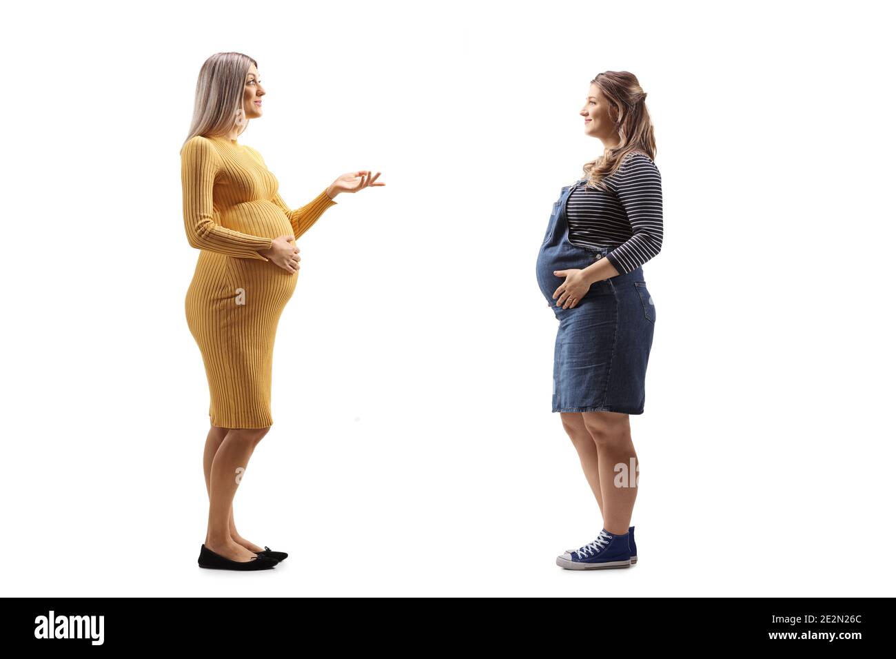 Full length profile shot of two pregnant women talking to eachother isolated on white background Stock Photo