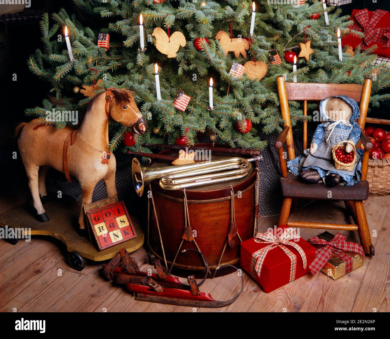 1980s ANTIQUE TOYS MUSICAL INSTRUMENTS UNDER A BLUE SPRUCE CHRISTMAS TREE DECORATED WITH SUGAR COOKIES APPLES AND LIT CANDLES - kx9753 TEU001 HARS MERRY AND LIT DIRECTION A PAINTED SPRUCE DECEMBER CONNECTION CONCEPTUAL DECEMBER 25 STILL LIFE STYLISH HOBBY HORSE RAG DOLL BUGLE JOYOUS ICE SKATES OLD FASHIONED Stock Photo