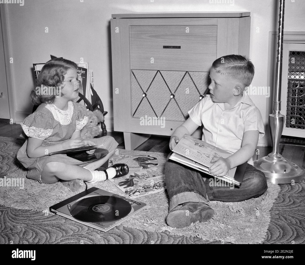 1940s 1950s BOY AND GIRL BROTHER SISTER SITTING BEFORE RECORD PLAYER PHONOGRAPH LISTENING TO MUSIC PLAYING RECORDS - m167 BAU001 HARS MALES ENTERTAINMENT SIBLINGS SISTERS B&W PHONOGRAPH STEREO BEFORE HIGH ANGLE SIBLING RPM 78 GROWTH JUVENILES TOGETHERNESS ALBUMS BLACK AND WHITE CAUCASIAN ETHNICITY OLD FASHIONED Stock Photo