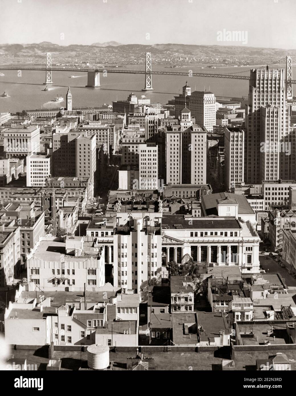 1930s 1940s DOWNTOWN CITY BUILDINGS WITH WESTERN SECTION OF OAKLAND BAY BRIDGE IN BACKGROUND SAN FRANCISCO CALIFORNIA USA - q39320 CPC001 HARS BRIDGES JOIN OLD FASHIONED SECTION SUSPENSION TOWERS Stock Photo