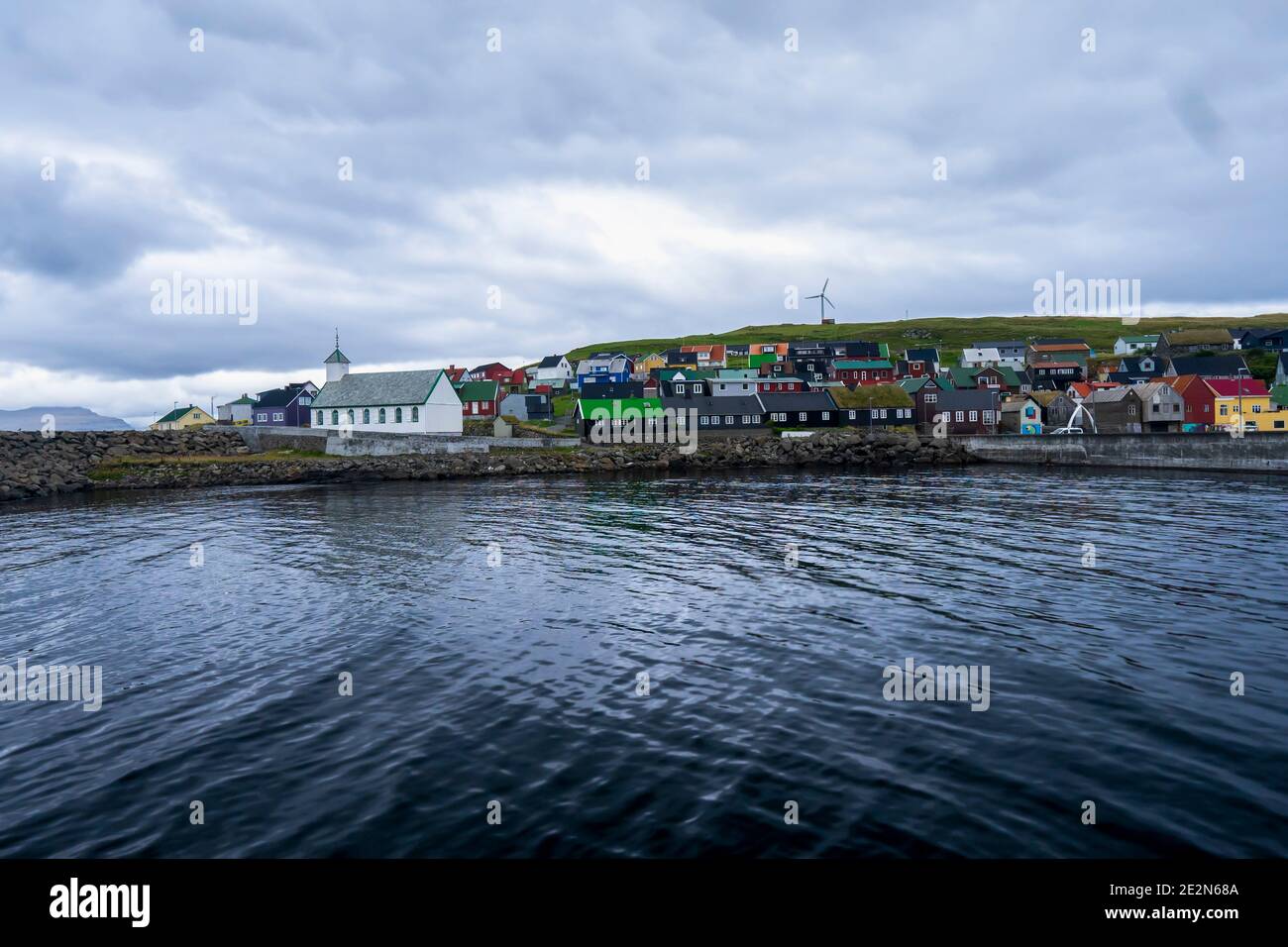 Nolsoy - small picturesque island in the Faroe Islands reached from Torshavn. View of a wooden, traditional church, colorful houses with grass roofs. Stock Photo