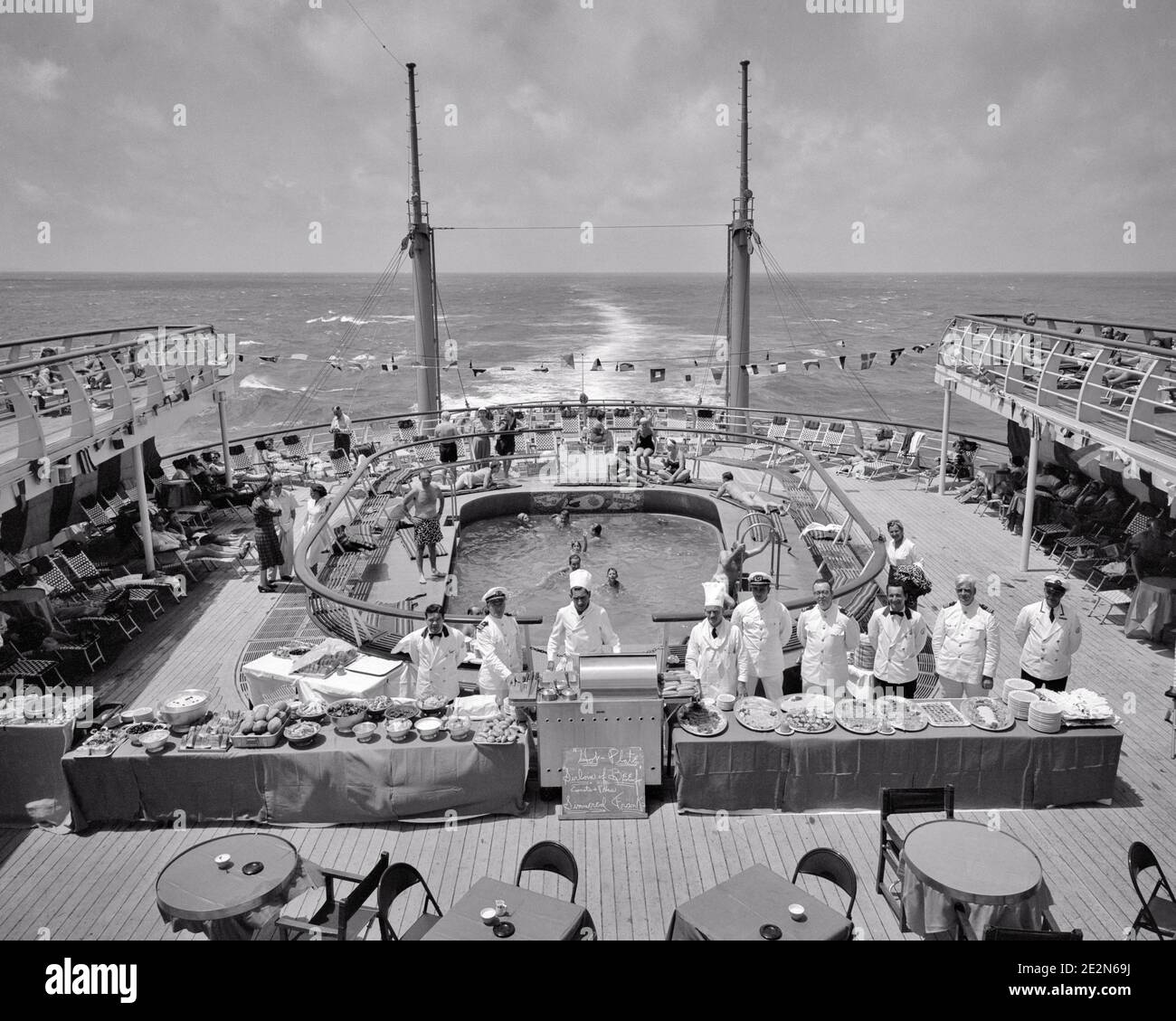 1950s BUFFET LUNCH SERVING CREW STAFF ASSEMBLED ABOARD THE AFT DECK BY SWIMMING POOL ON THE CRUISE SHIP SS INDEPENDENCE AT SEA - s11969 RGE001 HARS BUFFET LUXURY COPY SPACE FULL-LENGTH LADIES PERSONS MALES PROFESSION SHIPS TRANSPORTATION AFTER B&W TIME OFF SKILL TEMPTATION OCCUPATION SKILLS HIGH ANGLE ADVENTURE LEISURE CUSTOMER SERVICE TRIP GETAWAY CAREERS RECREATION LABOR PRIDE AT BY ON THE EMPLOYMENT HOLIDAYS OCCUPATIONS CONCEPTUAL SERVERS STYLISH ASSEMBLED EMPLOYEE AFT SS STAFF TOQUE VACATIONS ABOARD BLACK AND WHITE FOOD PREPARATION LABORING OLD FASHIONED VESSEL Stock Photo
