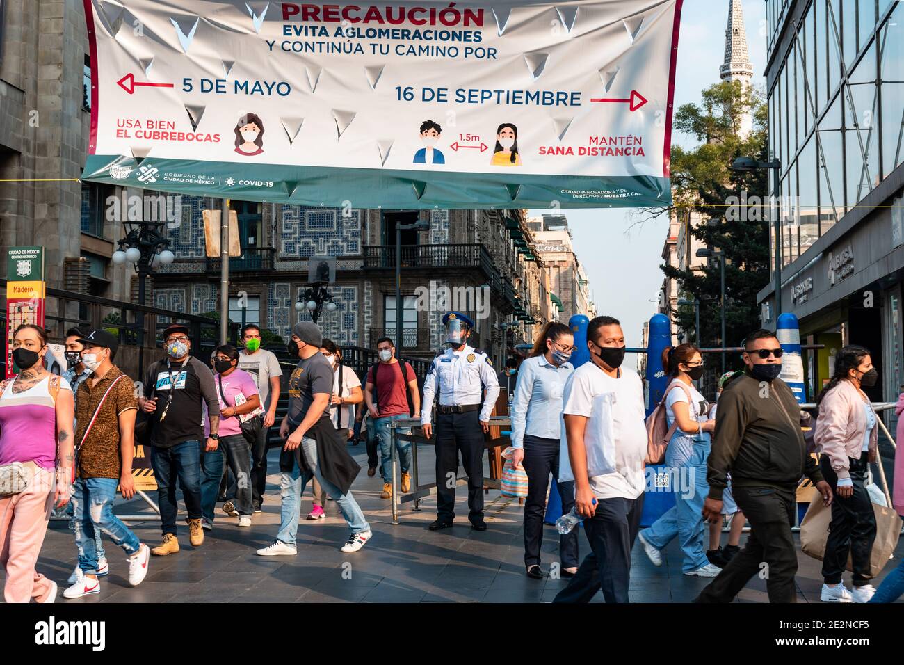 Crowd of ethnic people in masks walking past police officer with face