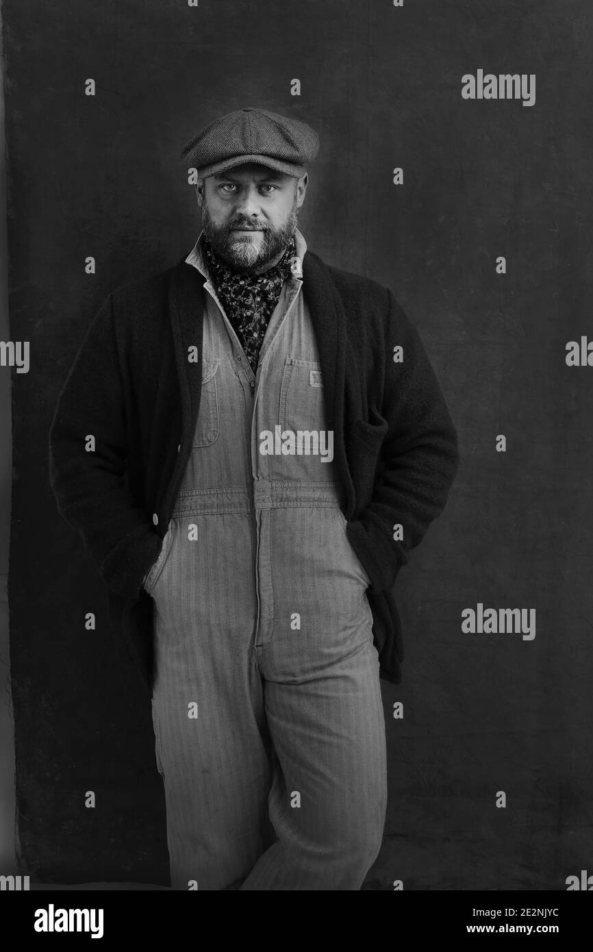 handsome man with beard and denim overall looking at camera. Stock Photo