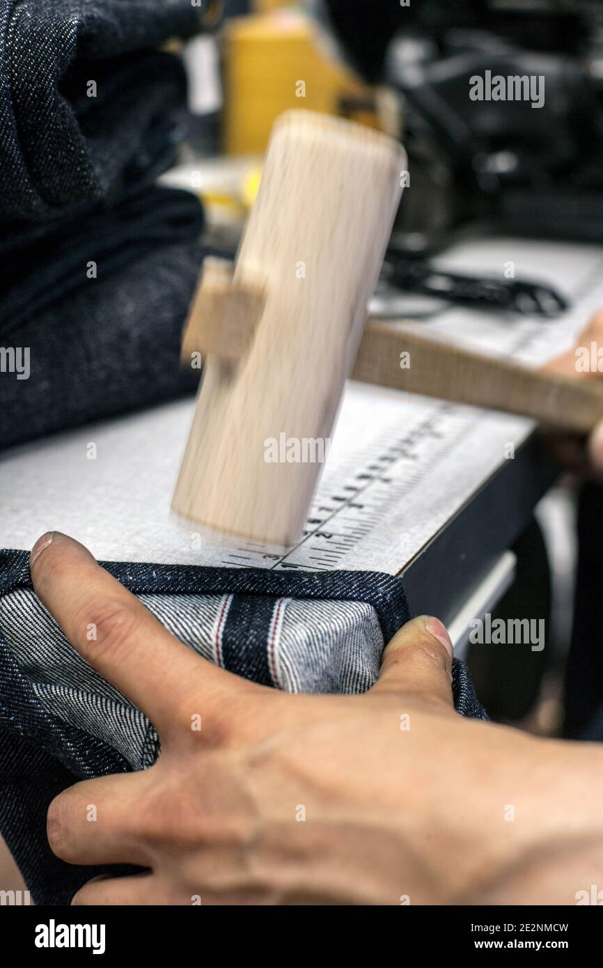 Shorten the Jeans and using hammer for bulky corners. Stock Photo