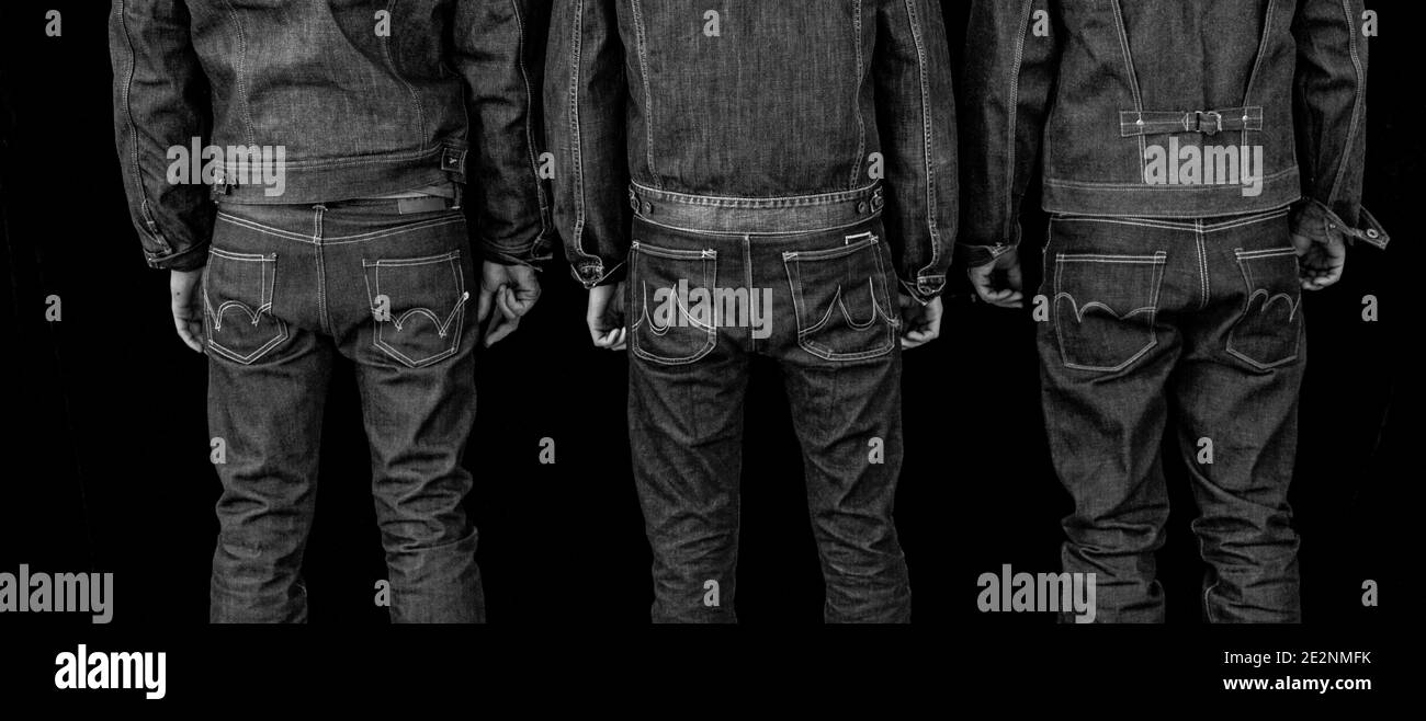 view from behind of three men wearing denim jeans .three man rear view Stock Photo