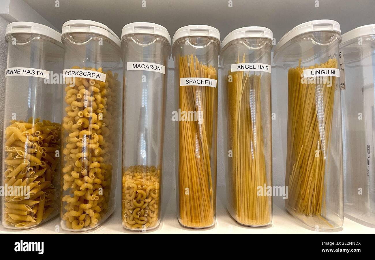 An organized pantry shelf with various types of pasta in plastic