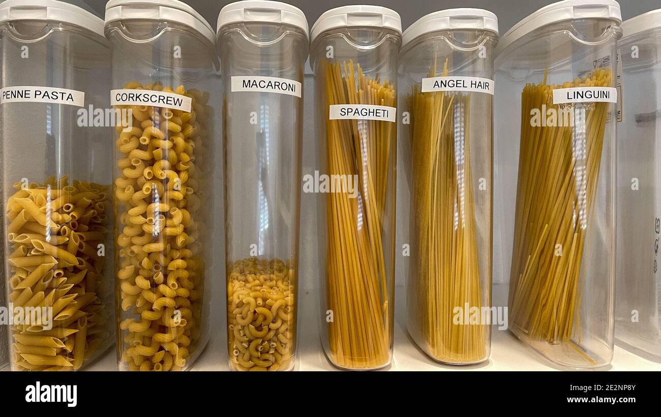 An organized pantry shelf with various types of pasta in plastic
