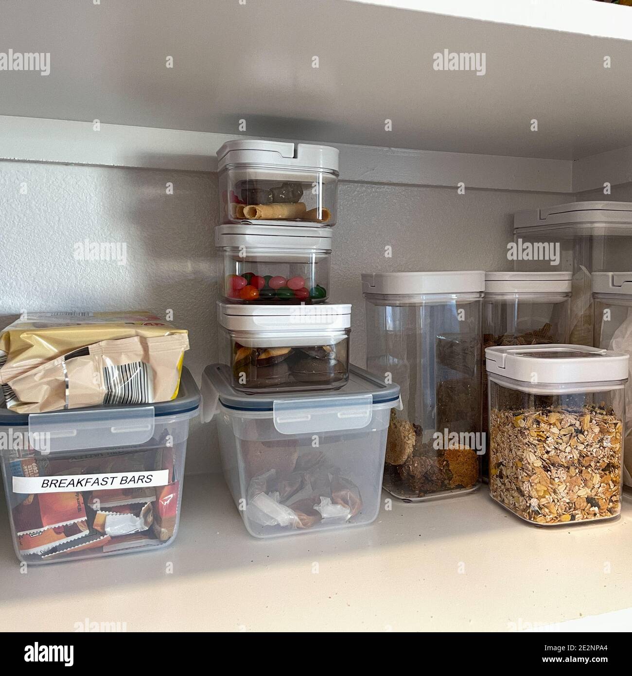 An organized pantry shelf with various types of cookies, cereal and