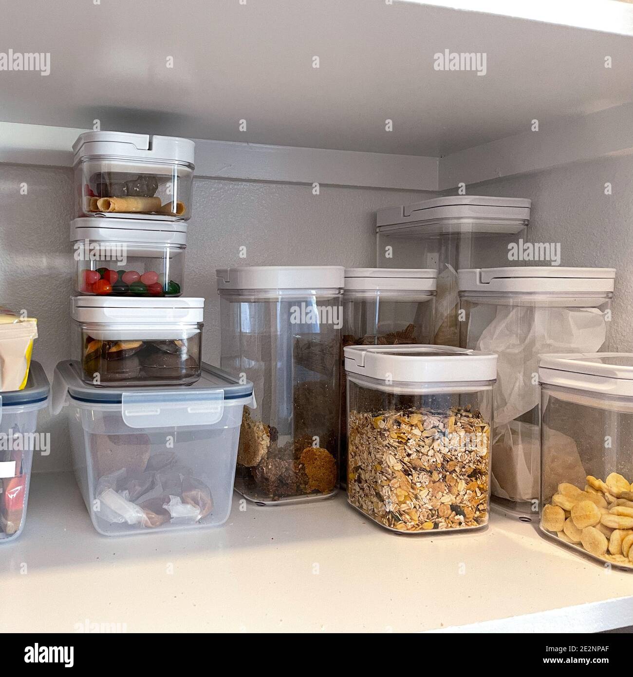 An organized pantry shelf with various types of cookies, cereal and