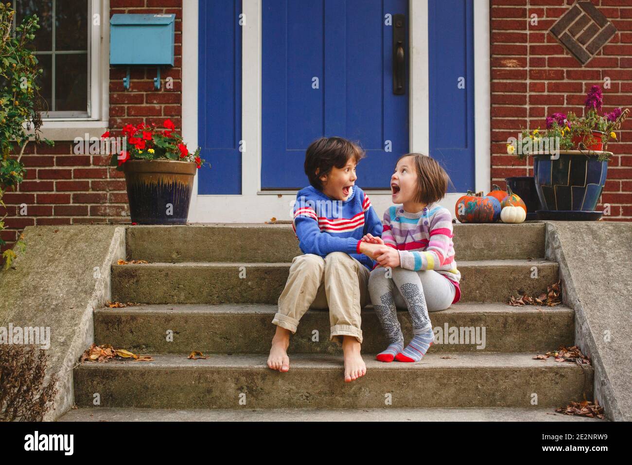 A little boy and girl sitting on stoop yell out loud  in joy together Stock Photo