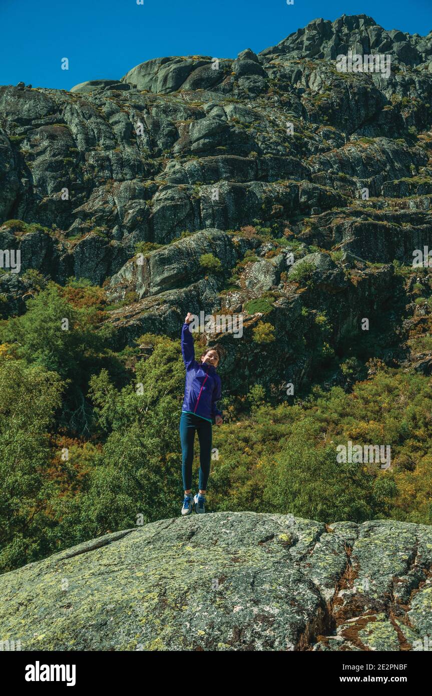 Little girl jumping on a big rock covered by lichens at the highlands of Serra da Estrela. The highest mountain range in continental Portugal. Stock Photo