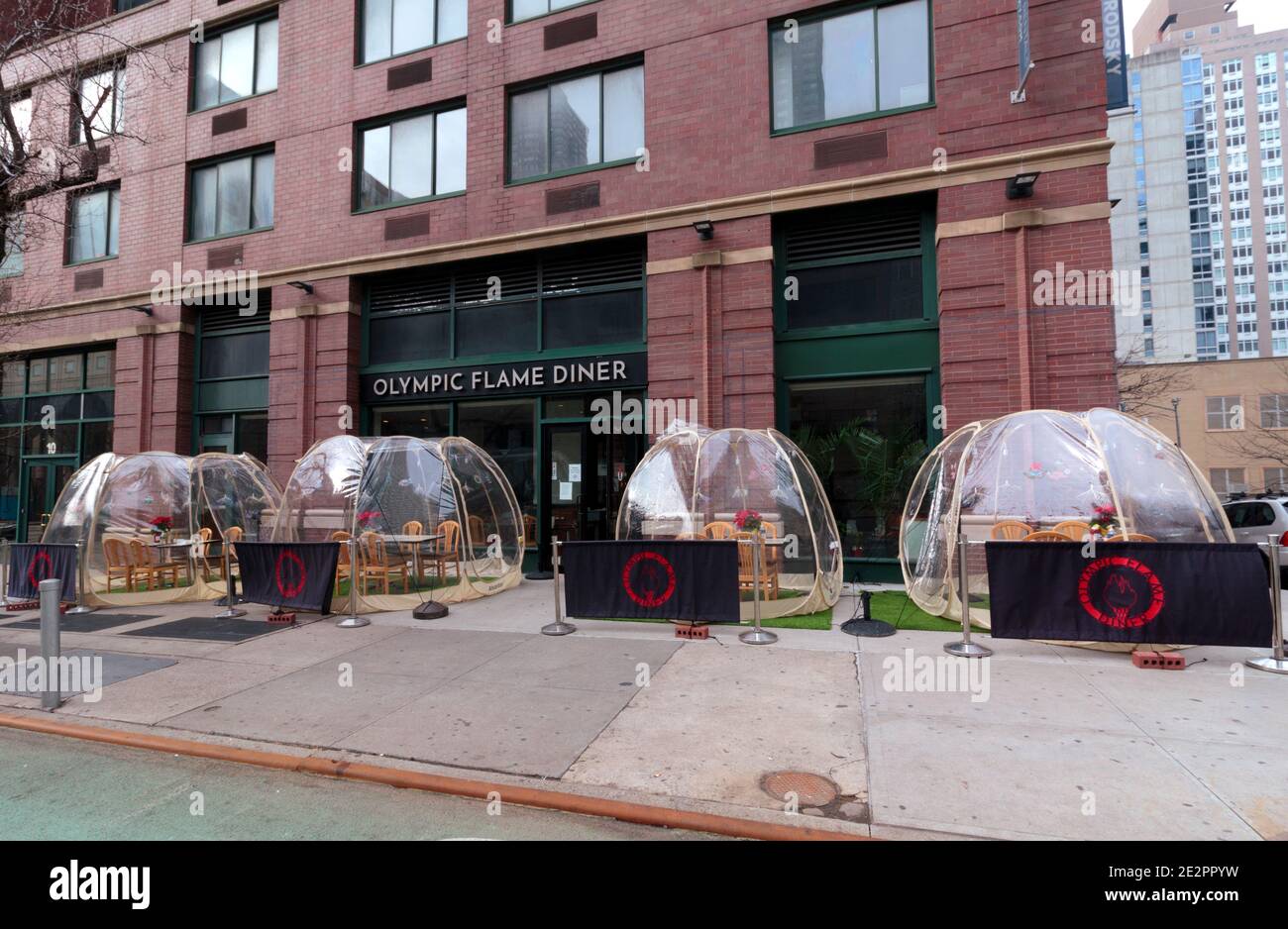 a row of plastic pop-up dining pods on the sidewalk in front of the Olympic Flame Diner in Manhattan to comply with covid dining restrictions Stock Photo