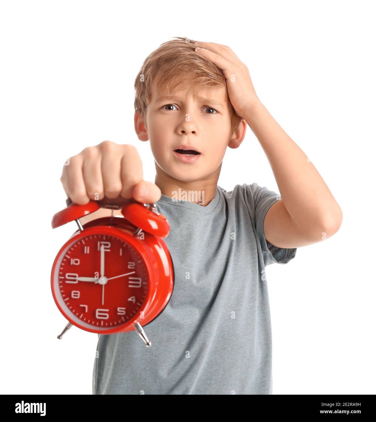 Emotional little boy with alarm clock on white background Stock Photo