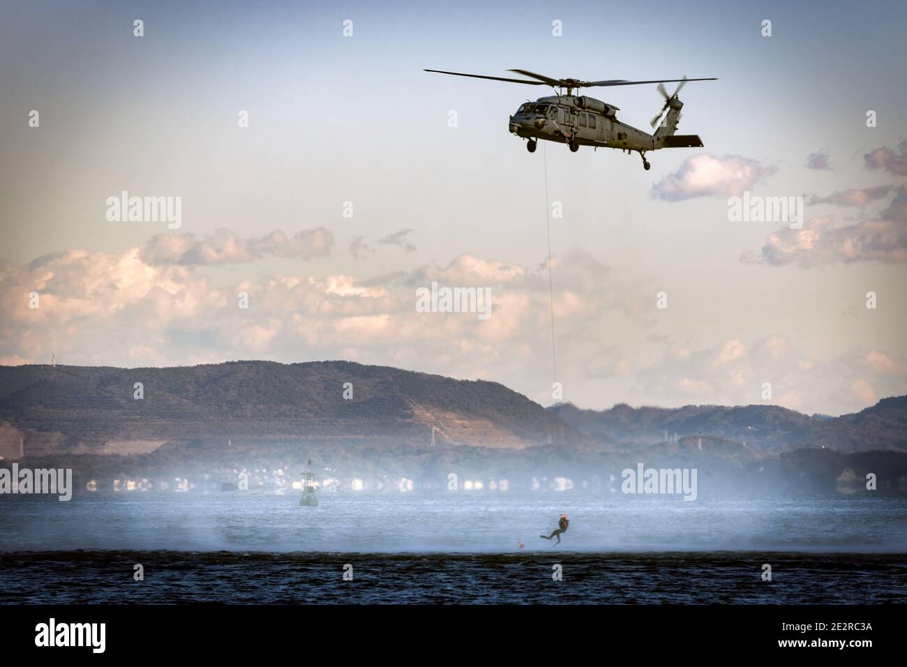 A US Navy MH-60 helicopter hovers while rescue swimmers train in Tokyo Bay. Stock Photo