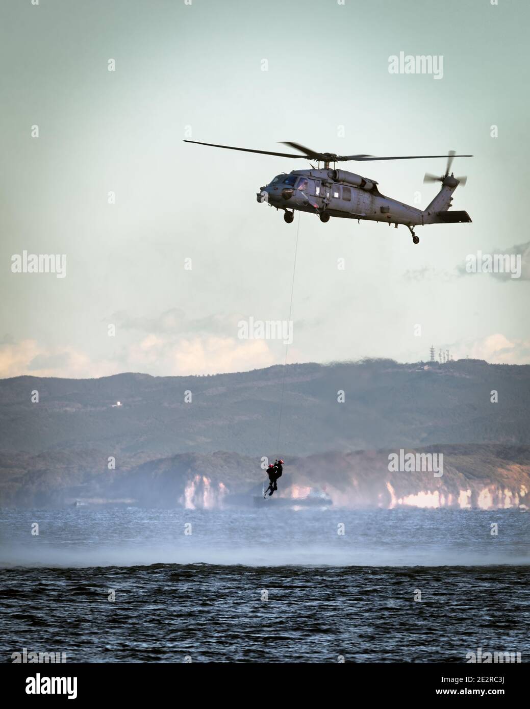 A US Navy MH-60 helicopter hovers while rescue swimmers train in Tokyo Bay. Stock Photo