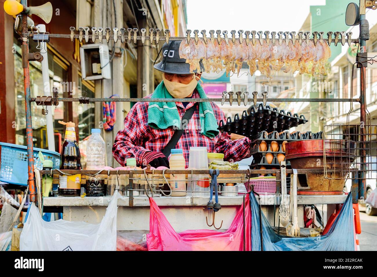 China Town, Bangkok, Thailand - Nov. 14, 2020: A street food seller must always wear a protective face mask while selling his food. Stock Photo